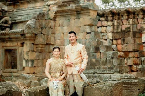Free Two adults in traditional attire posing in front of an ancient stone temple. Stock Photo