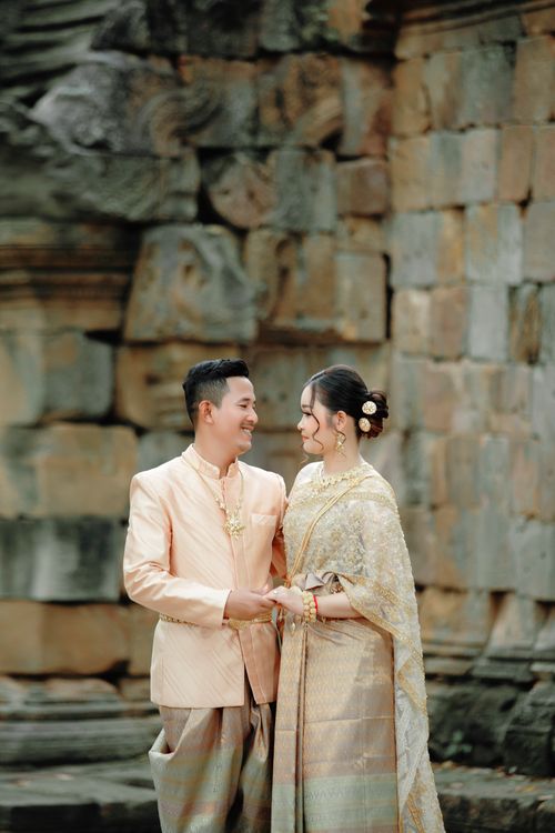 Free Couple in traditional attire posing in front of ancient temple walls, exuding cultural charm. Stock Photo