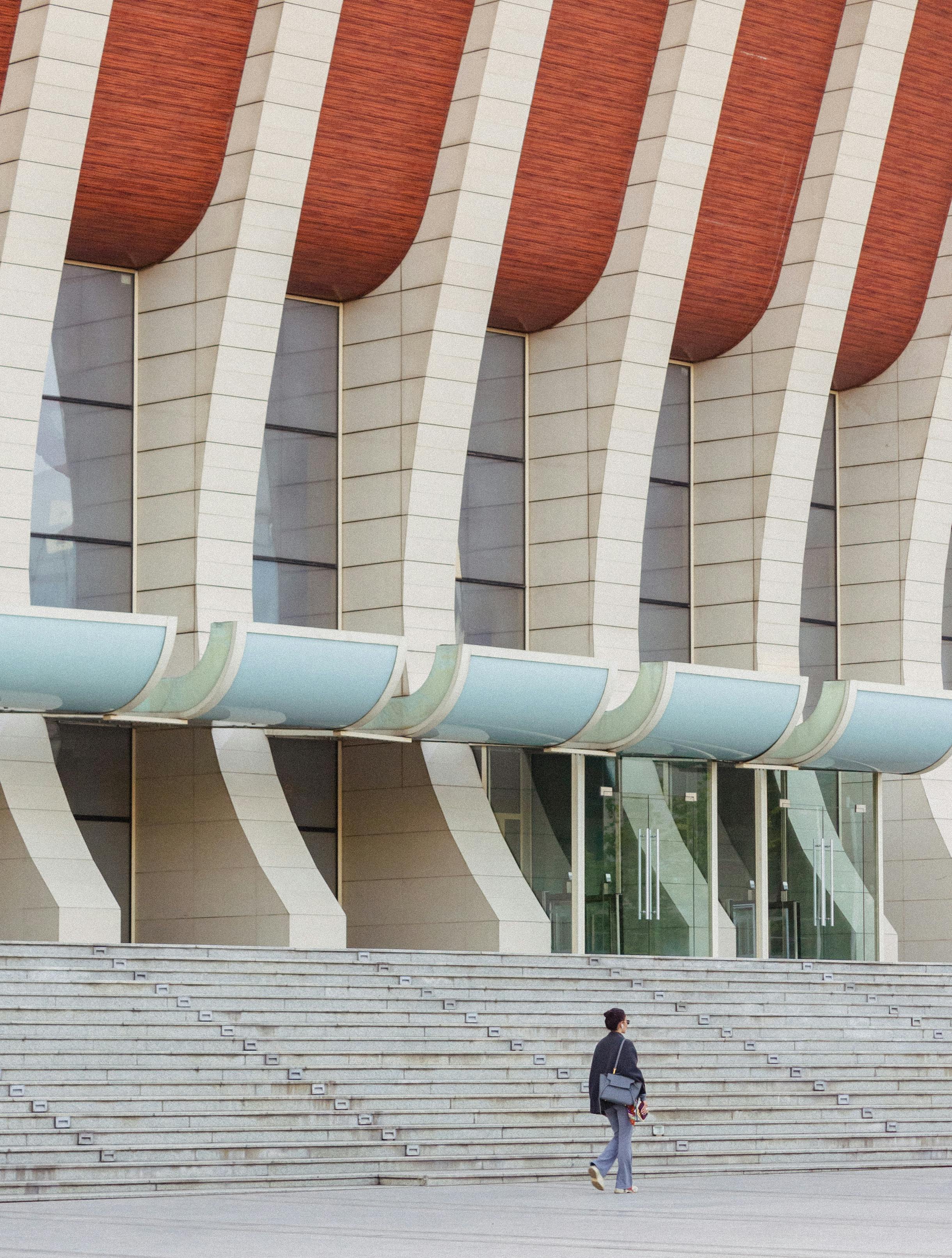 A striking modern architectural facade with a person walking, highlighting urban design.
