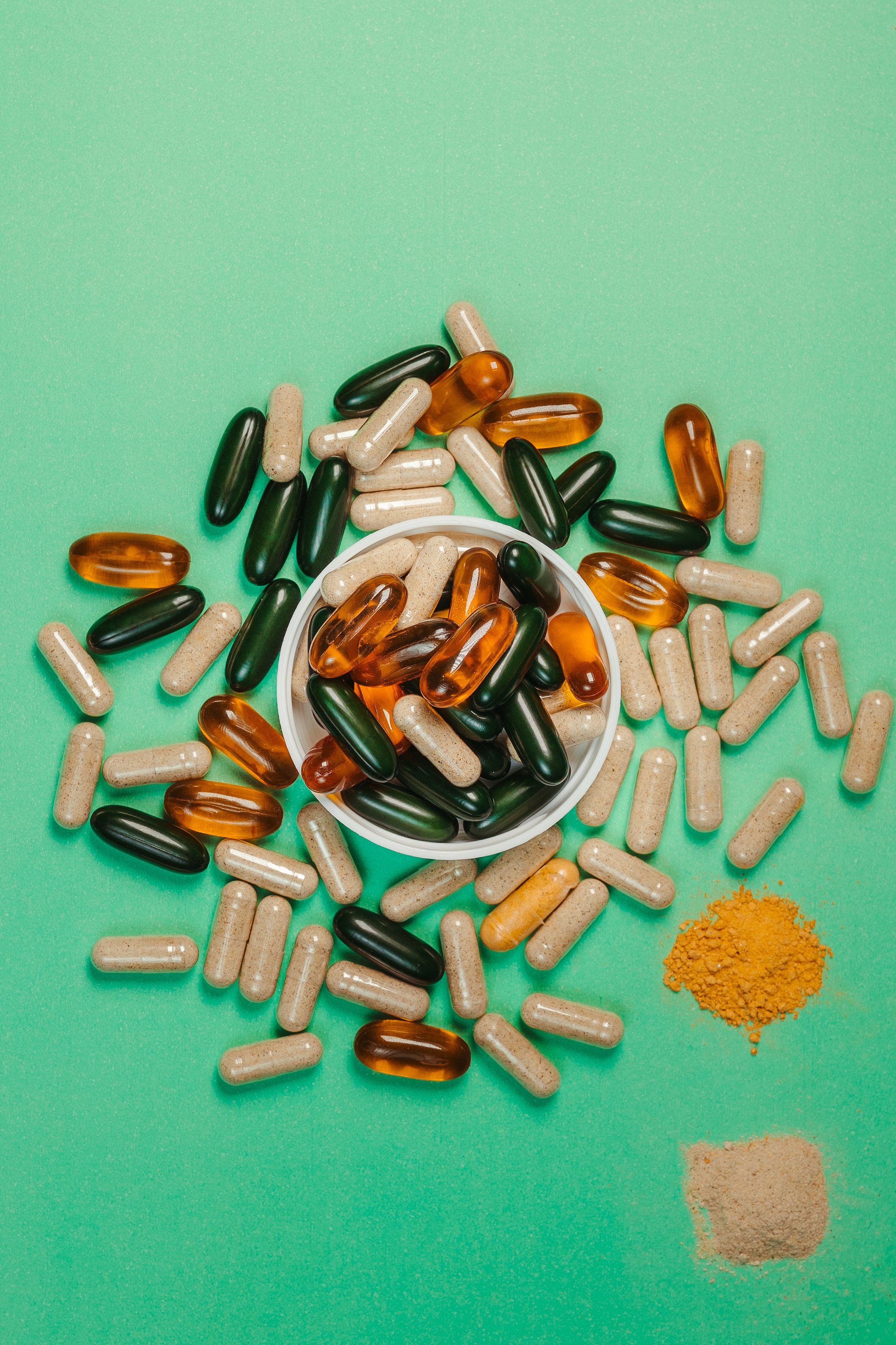 multi colored capsules and powder on green background