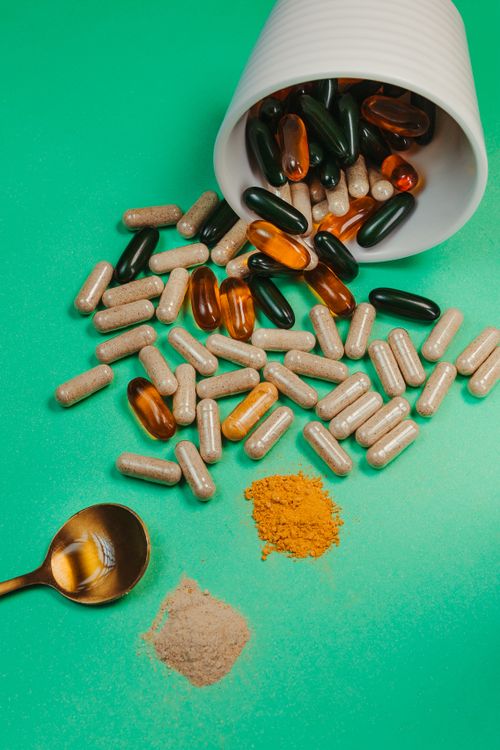 Free Variety of capsules and powders with a spoon on green backdrop. Ideal for health and wellness themes. Stock Photo
