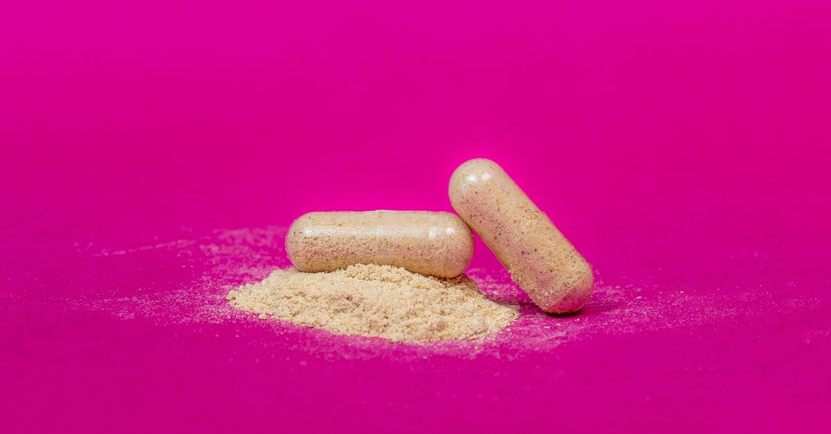 Close-up of two supplement capsules and powder on a vibrant pink background. - Evidence evidence guide for lactoferrin immune meta-analysis