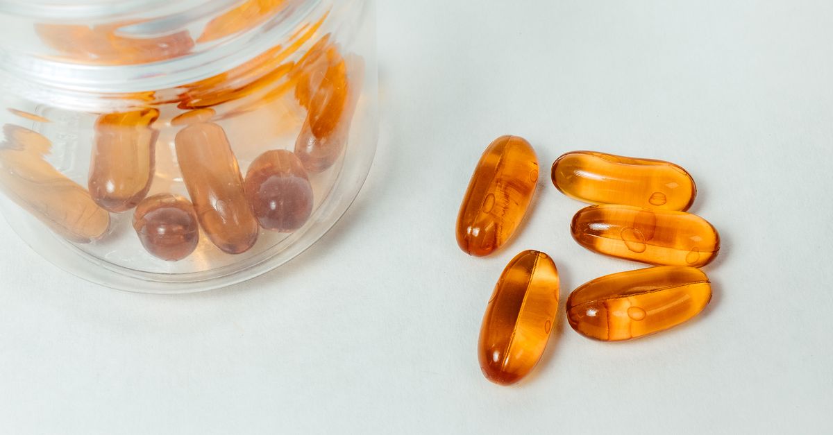 Glass container with amber capsules spilling out on a white background. - Evidence evidence guide for vitamin D sleep randomized trial