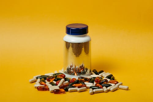 Бесплатное стоковое фото с бутылка таблеток, желтый фон, капсулы