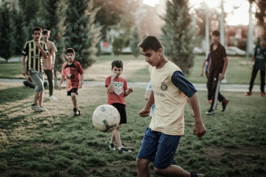 A group of boys play football in an urban park during the day, showcasing childhood joy.
