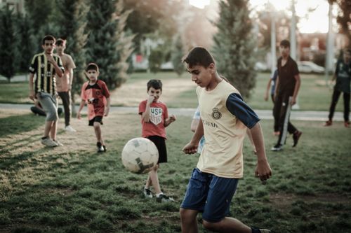Free A group of boys play football in an urban park during the day, showcasing childhood joy. Stock Photo