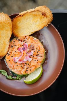 Gourmet salmon tartar with lime and nigella seeds, served with toasted baguette slices.