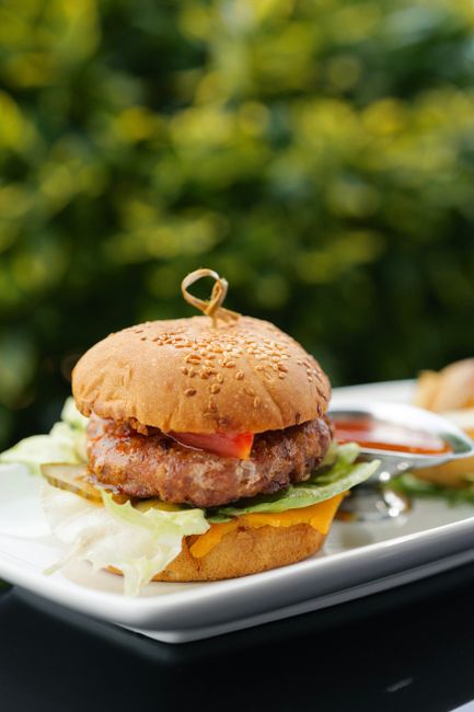 Mouth-watering cheeseburger served with lettuce, tomato, and pickles on a sesame bun.