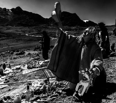 A person performs a traditional ritual in a mountainous rural setting, emphasizing cultural heritage.