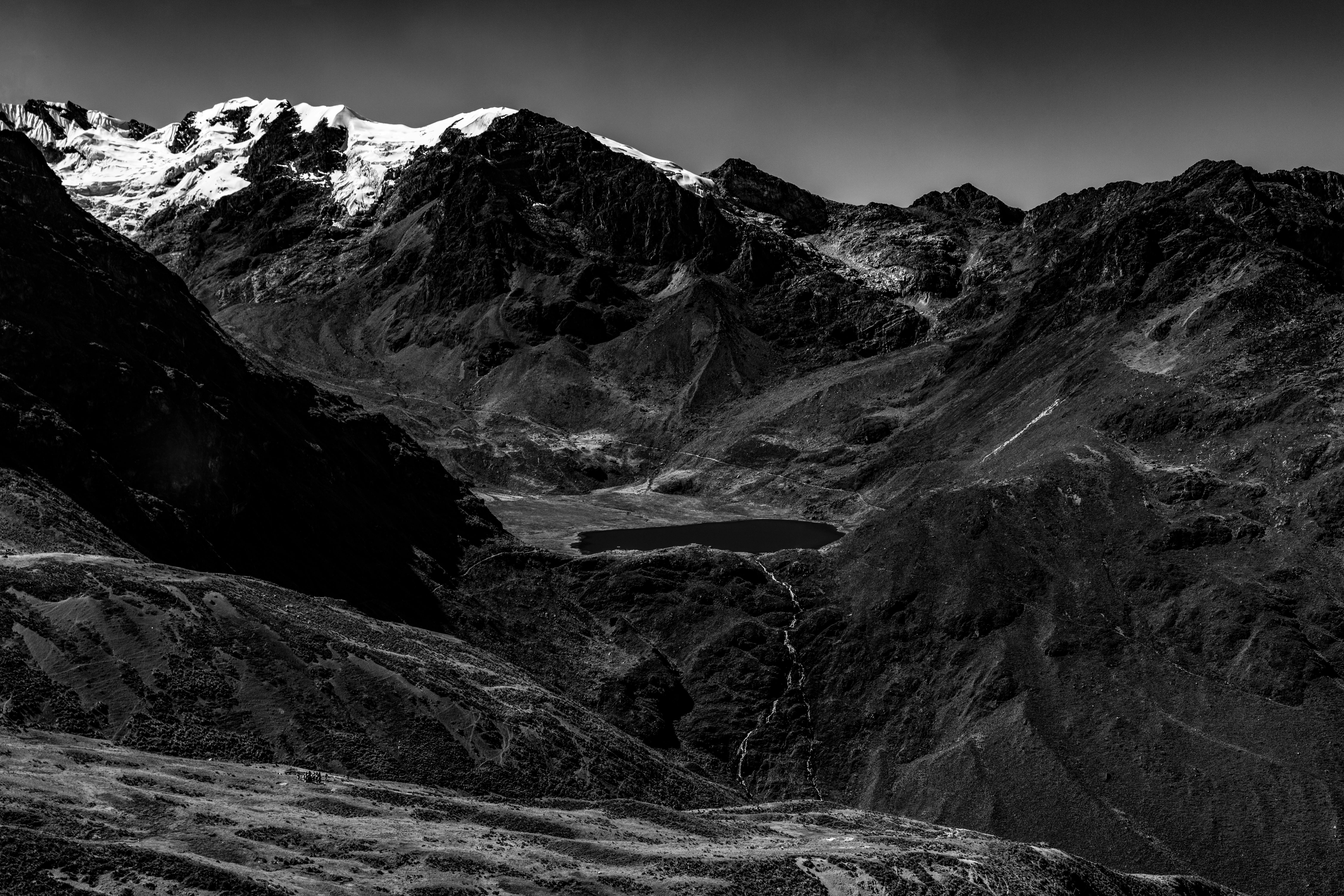 A dramatic black and white photo of majestic mountains and a serene lake.