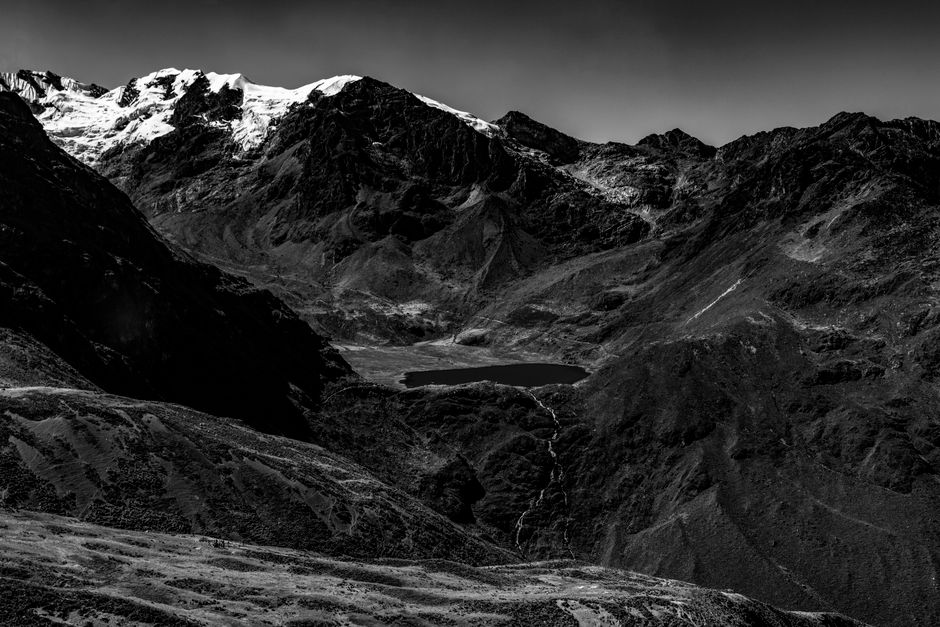 A dramatic black and white photo of majestic mountains and a serene lake.