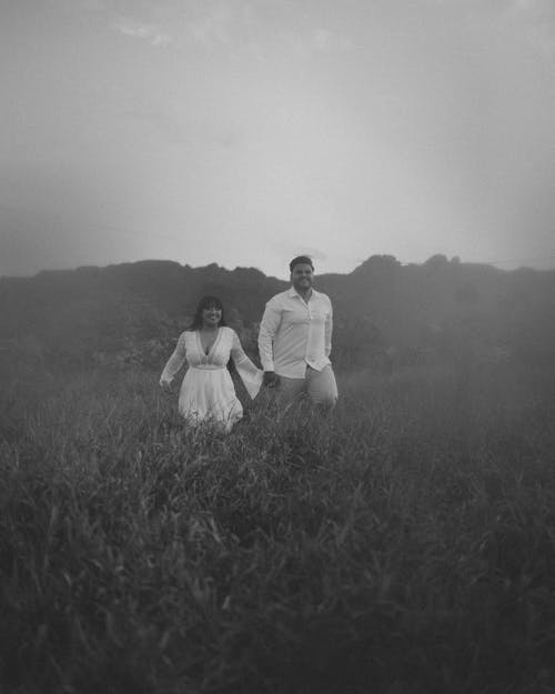 Couple Holding Hands and Walking on Grassland under Fog