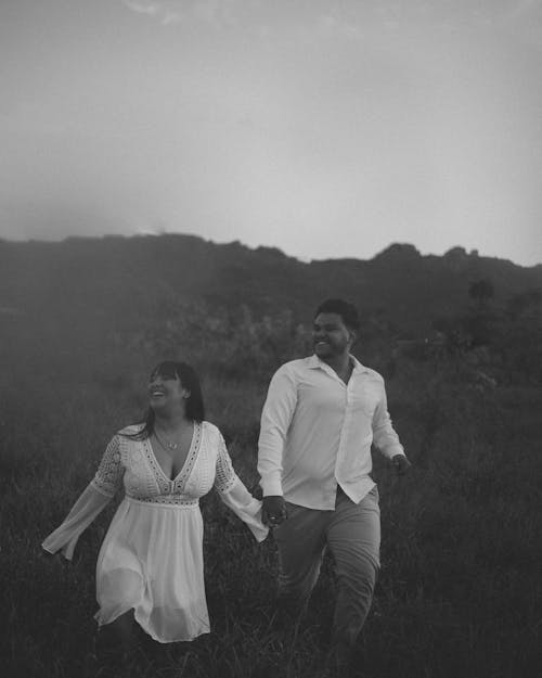 A Couple Holding Hands and Walking on the Field 