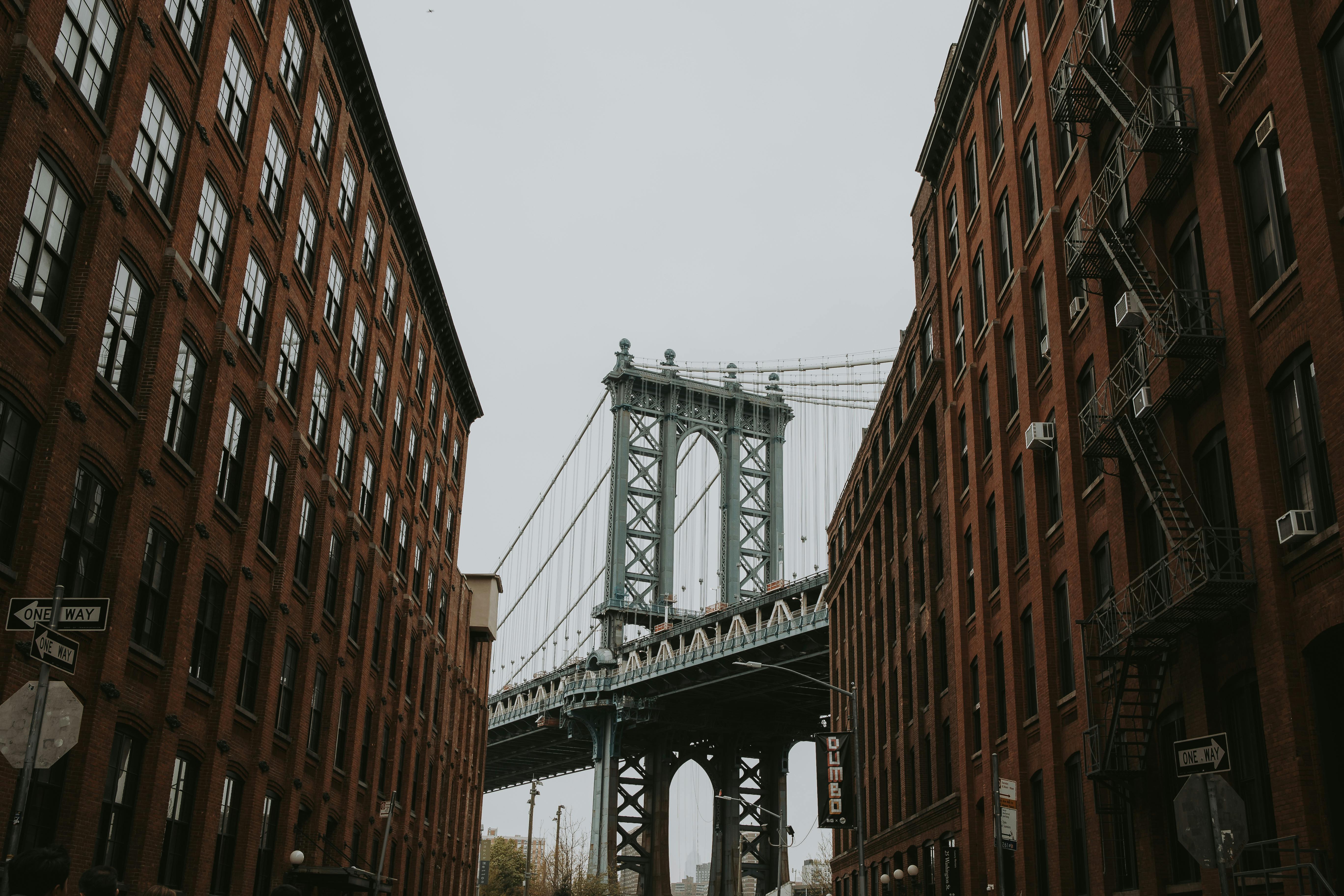 Iconic view of Manhattan Bridge framed by red brick buildings in DUMBO, New York City.