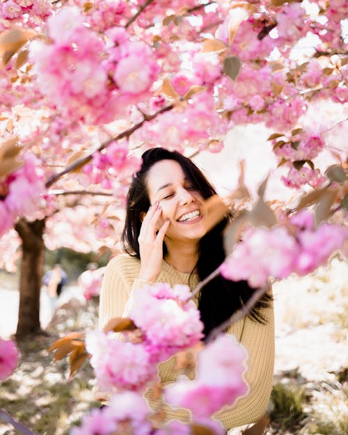 Young Woman Standing between Cherry Blossom Branches 