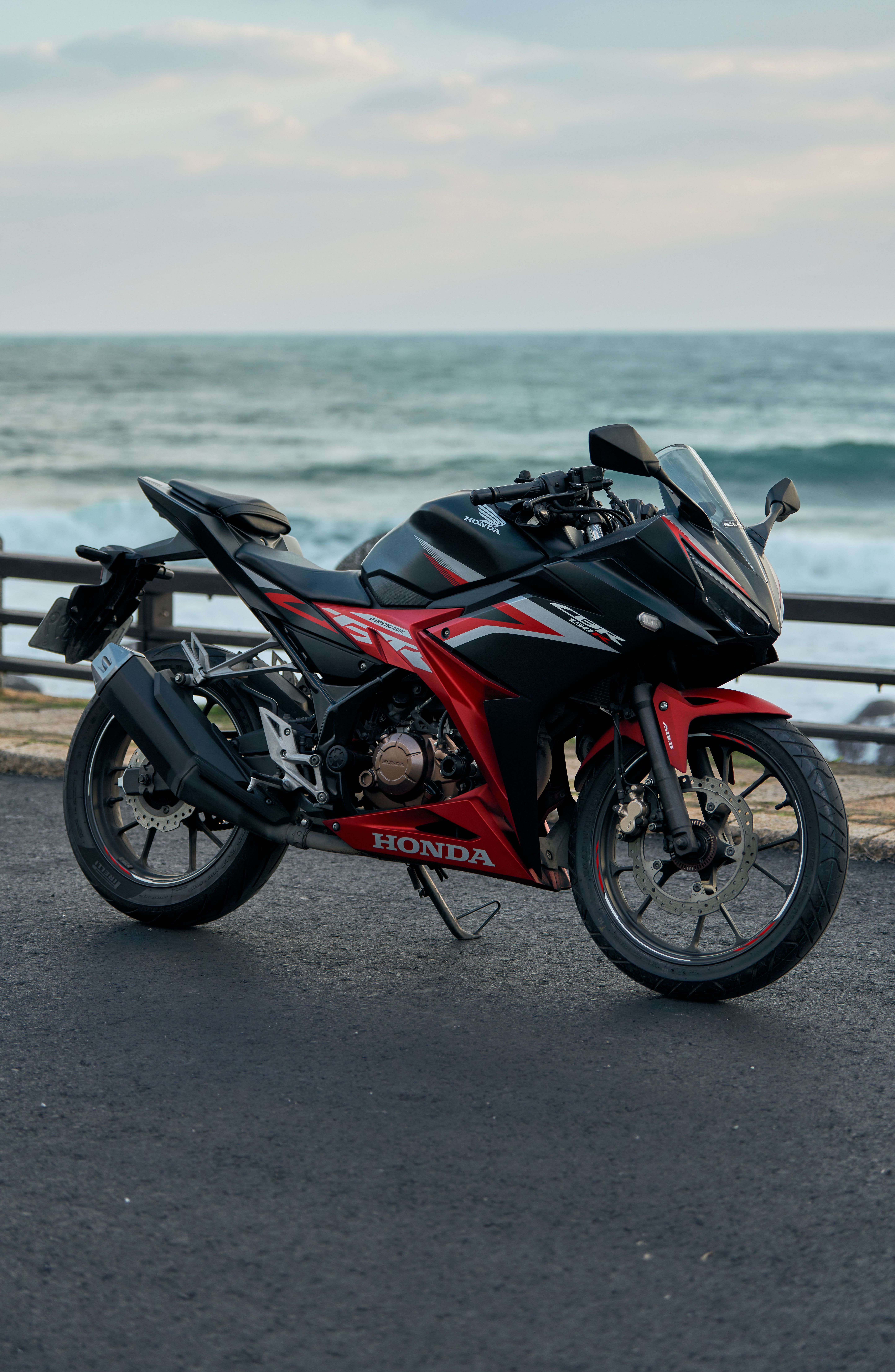 A sleek sport bike parked near the ocean, capturing the thrill of riding along the coast.