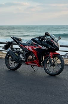 A sleek sport bike parked near the ocean, capturing the thrill of riding along the coast.