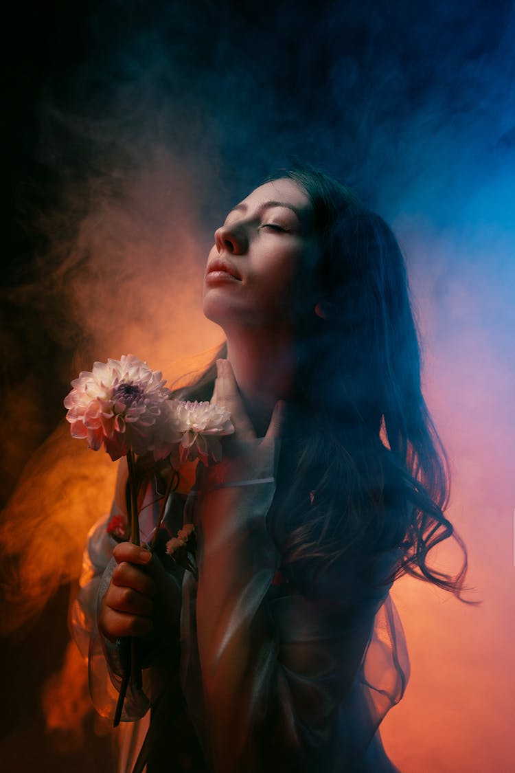 Young Woman Posing In Studio With Orange Lighting And Smoke 