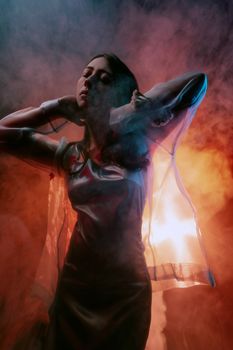 Fashion portrait of a woman with dramatic smoke and backlit lighting in a studio.
