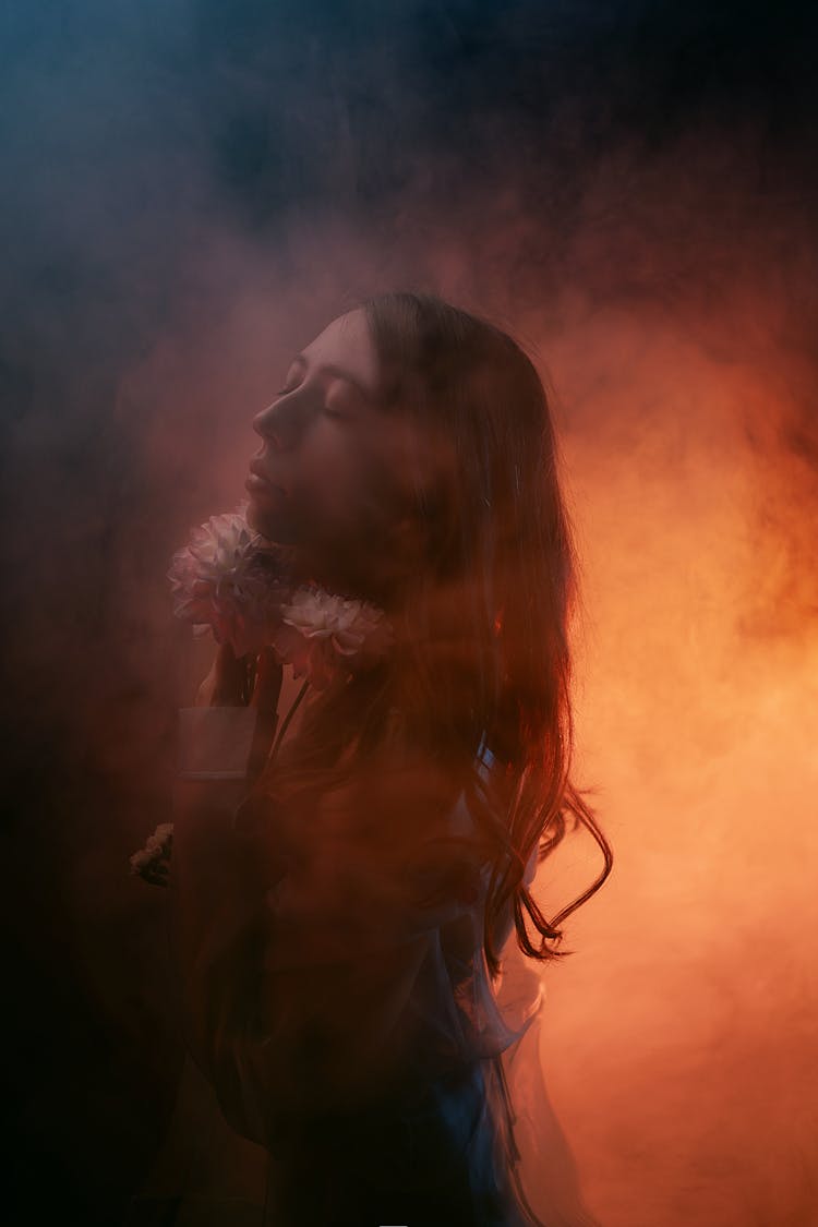 Studio Shot Of A Young Woman In Orange Lighting And Smoke 