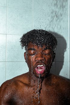Close-up of a shirtless man enjoying a refreshing indoor shower.