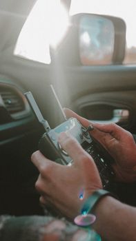 Hands holding a drone controller inside a car, showcasing modern technology and focus on detail.