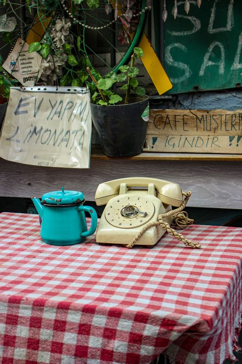 Free A vintage rotary telephone and teal teapot on a checkered tablecloth, evoking nostalgia. Stock Photo