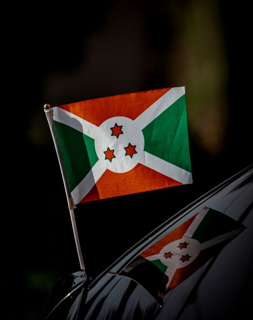 Free Burundi flag displayed outdoors with a clear reflection, symbolizing national pride. Stock Photo
