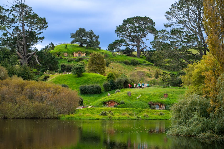 best maya tours commission for travel agents - Lush green landscape of Hobbiton with iconic hobbit holes and serene lake reflecting the vibrant scenery.