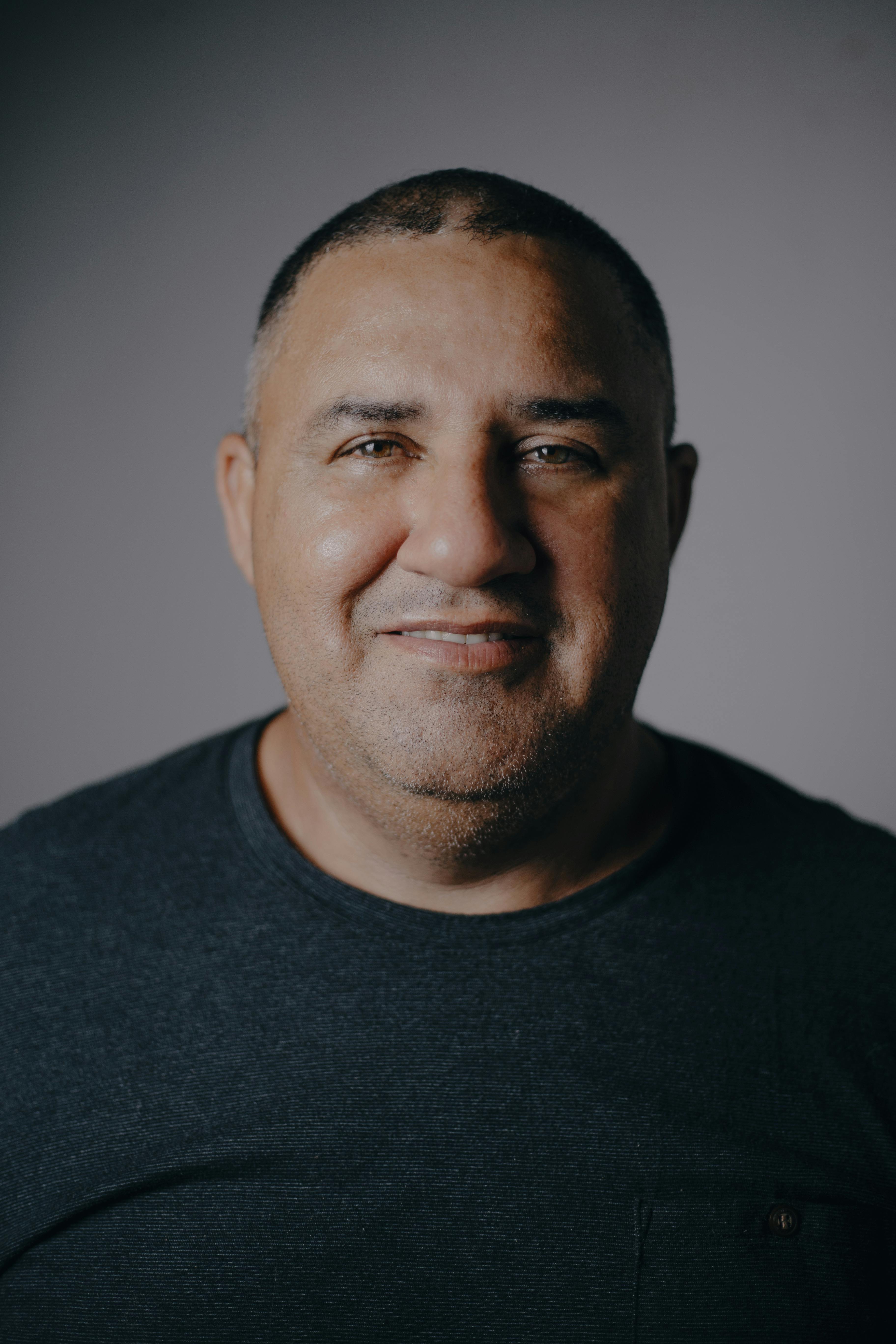 Portrait of a friendly middle-aged man smiling warmly in a studio setting.