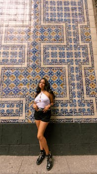 A stylish young woman stands by the decorative tile wall at Casa de los Azulejos, Mexico City.