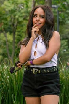 Young woman in stylish summer attire outdoors, featuring a halter top and shorts.