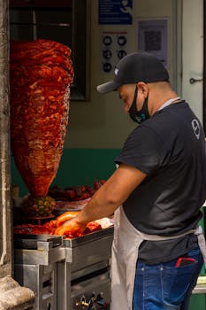 A street vendor skillfully prepares shawarma meat outdoors in a vibrant city setting.