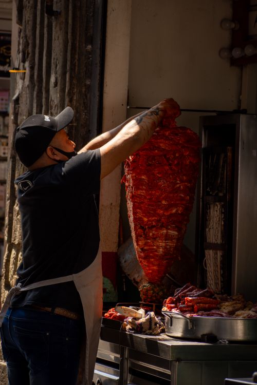 Free A man prepares a large skewer of seasoned meat for street food cooking outdoors. Stock Photo