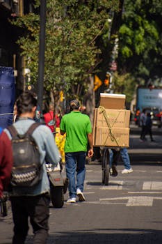 Man with bicycle and boxes on a busy city street, urban logistics.