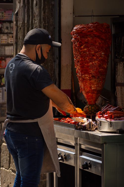 Free Street vendor preparing shawarma kebab meat in an urban food stall setting. Perfect for food and culture themes. Stock Photo