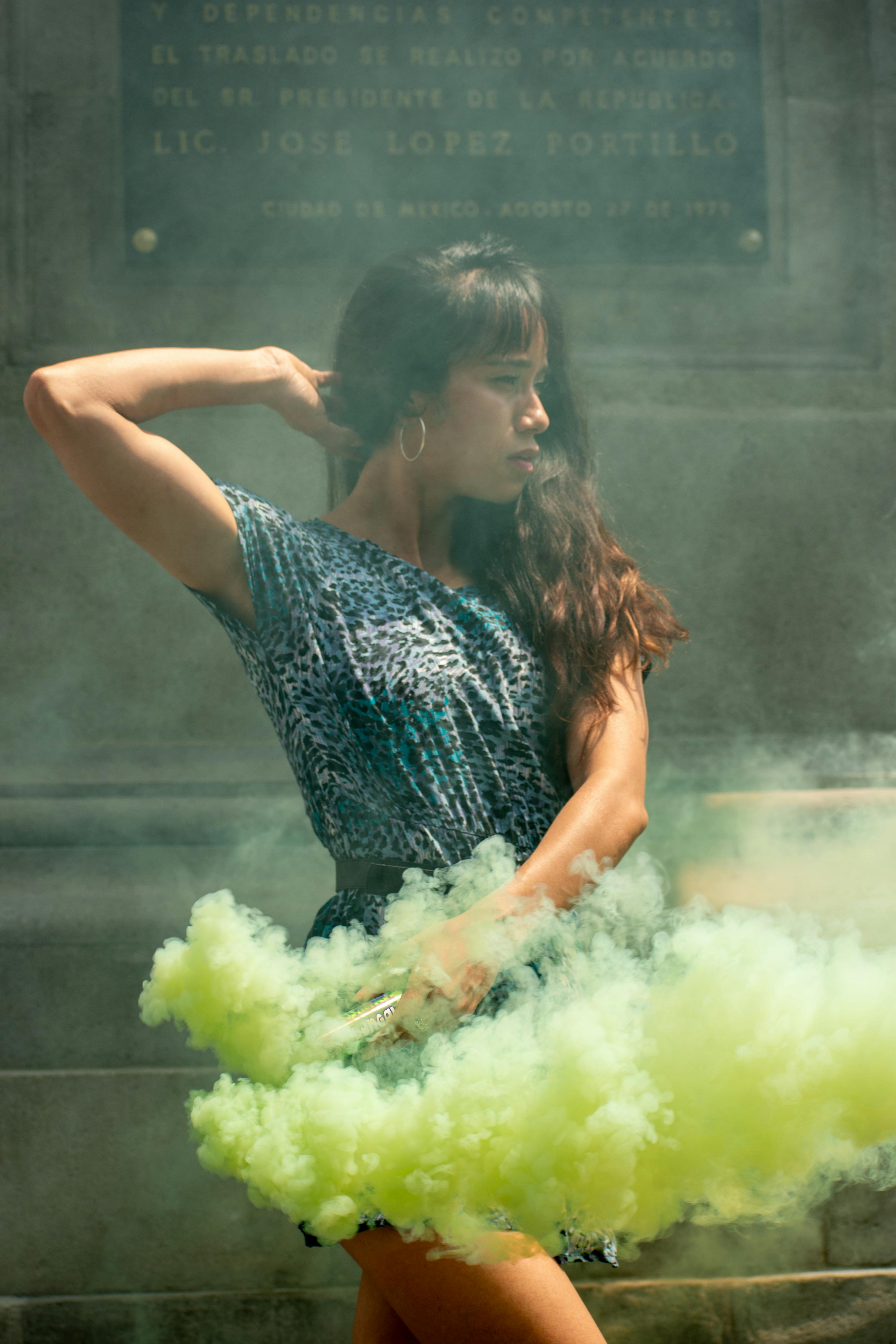 A young woman poses with vibrant smoke effects in Manuel Tolsa Square, Mexico City.