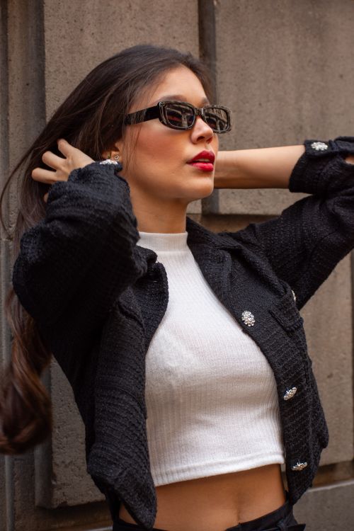 Free Fashionable woman with sunglasses and crop top poses against an urban background. Stock Photo