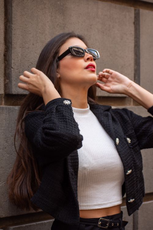 Free Elegant woman in sunglasses and chic outfit posing confidently against a textured wall. Stock Photo