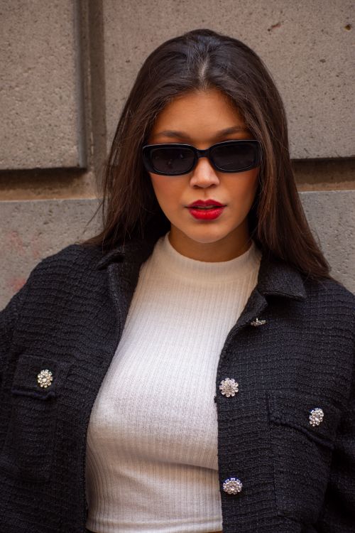 Free Portrait of a fashionable woman with red lips wearing a black jacket and sunglasses against a concrete wall. Stock Photo