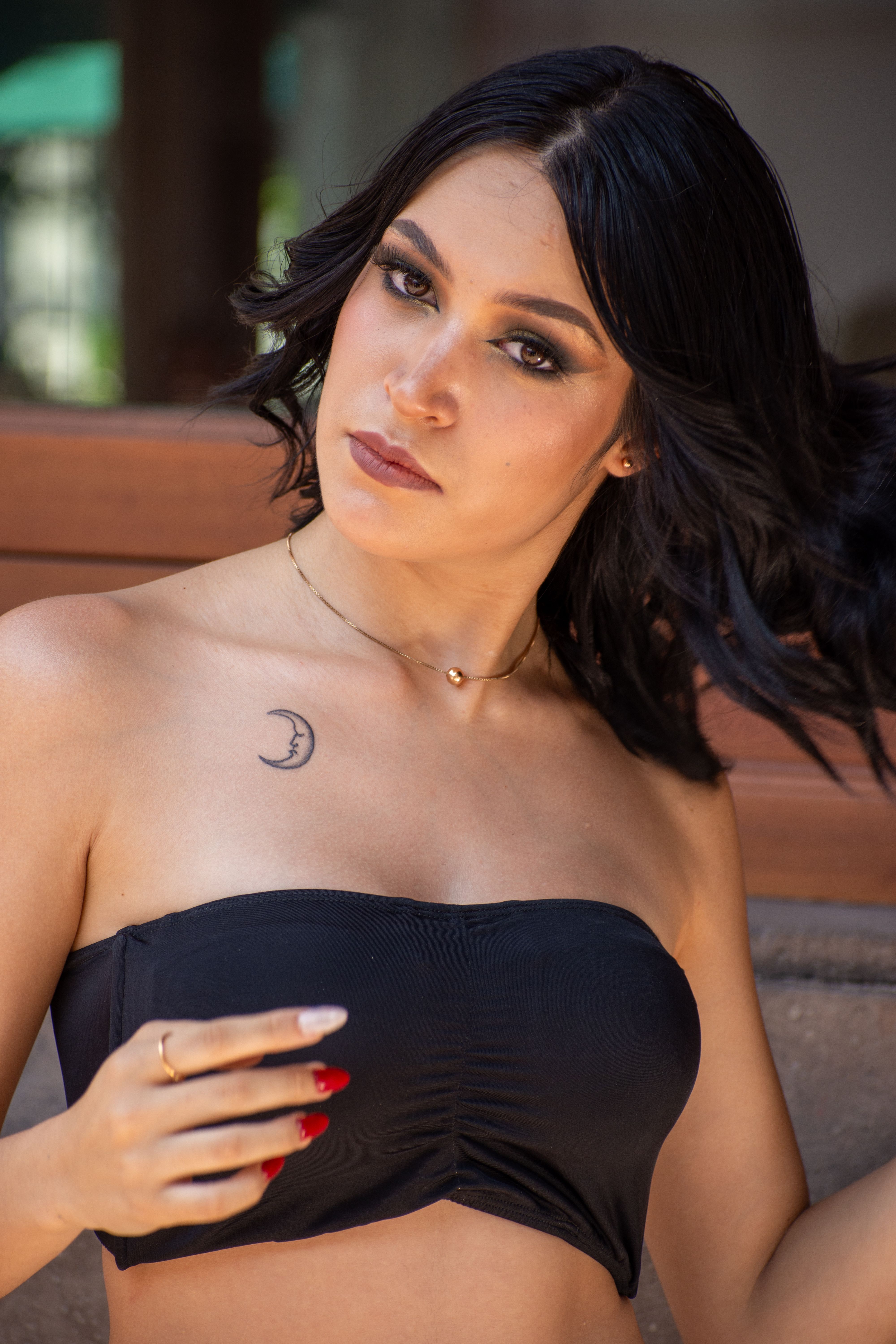 Stylish brunette woman in a bandeau bra posing confidently outdoors. Fashion photography at its finest.
