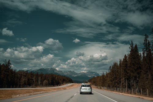 A car driving down a road with mountains in the background