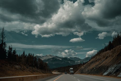 A truck driving down a highway with mountains in the background