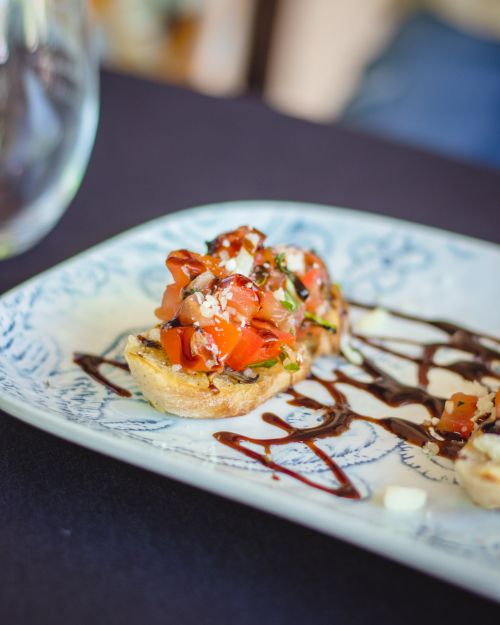 Free Top-down view of gourmet bruschetta with tomatoes and herbs on a decorative plate. Stock Photo