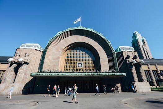 Helsinki's iconic Central Railway Station under a clear blue sky, bustling with activity.