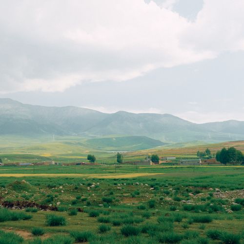 Free Scenic view of a tranquil valley and towering mountain range under a cloudy sky. Stock Photo
