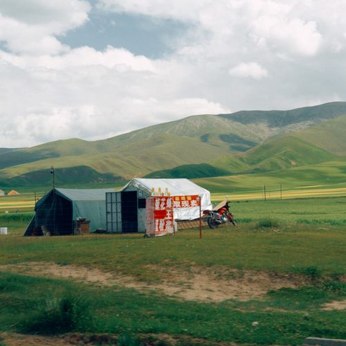 Free A rural market with tents set against rolling hills and a vast green landscape. Stock Photo