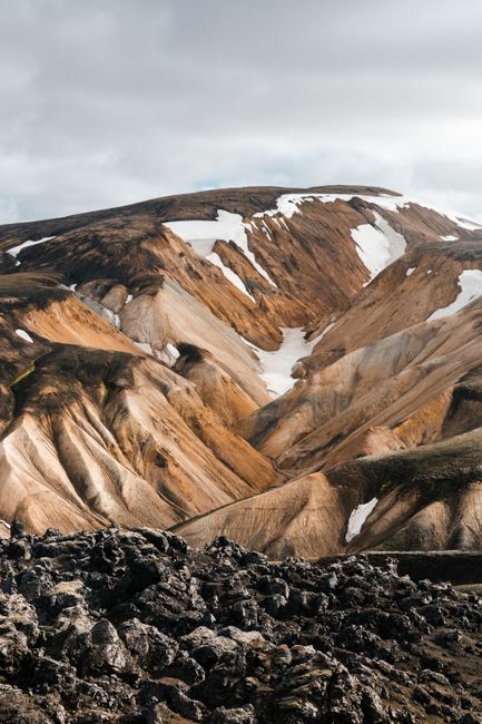 Captivating mountain scenery in Iceland featuring unique rock formations and scattered snow patches.