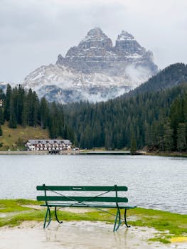 A picturesque view from a bench overlooking a serene lake and the majestic Tre Cime di Lavaredo in Veneto, Italy.