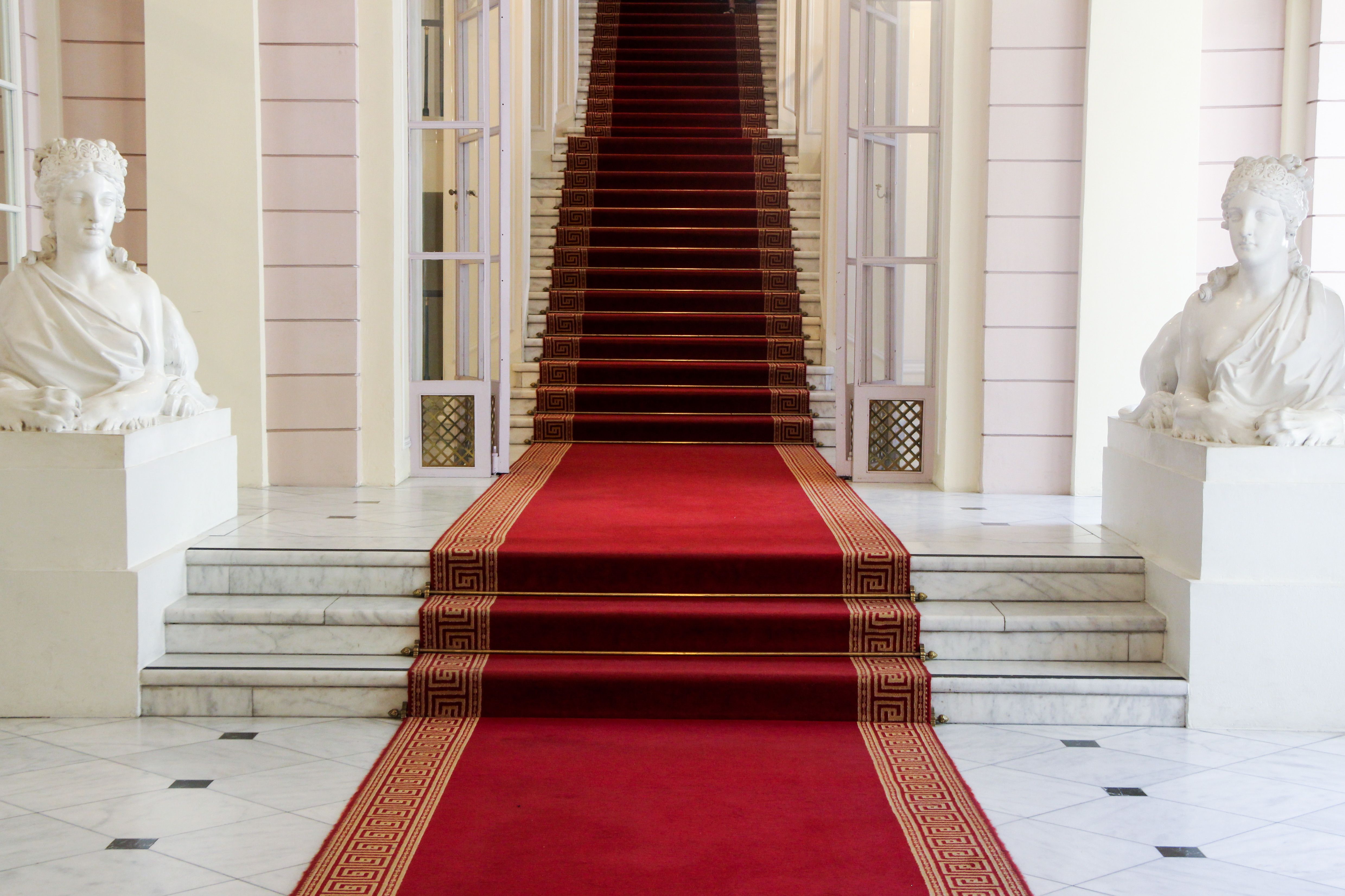 Majestic entrance with red carpet and statues at Albertina Museum in Vienna.